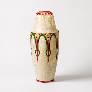 May include: A tall ceramic vase with a cream-colored mottled base. The exterior features a repeating pattern of green arches, red vertical accents, and blue and yellow geometric details around the neck and body, finished with a red rim.