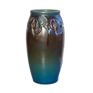 May include: A ceramic vase with a gradient of colors, transitioning from a deep teal at the base to a dark brown and teal at the top. The vase features embossed floral designs around the rim, with a glossy finish. The vase is approximately 10 inches tall.
