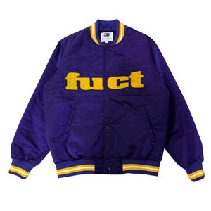 May include: A purple satin bomber jacket with the word "FUCT" in yellow block letters across the chest. The jacket has a ribbed collar, cuffs, and hem with yellow and white stripes. The jacket has a snap front closure and two front pockets.