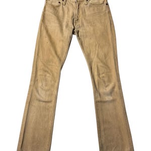 Op de afbeelding: Verbleekte, bruinbeige denim jeans met een klassiek ontwerp met vijf zakken. De jeans hebben een knoop- en ritssluiting, riemlussen en een lichte flare aan de onderkant van de broekspijpen. De jeans lijken versleten en hebben wat verkleuring.