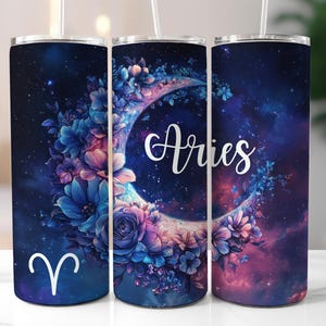 Könnte beinhalten: Drei Edelstahlbecher mit Galaxie- und Blumendesign. Die Becher zeigen eine Sichelmond mit Blumen und das Sternzeichen Widder. Die Becher sind dunkelblau, lila und rosa.