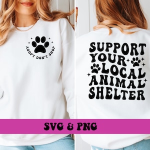 May include: White sweatshirt with a black paw print and the text "Adopt Don't Shop" on the front and the text "Support Your Local Animal Shelter" on the back.