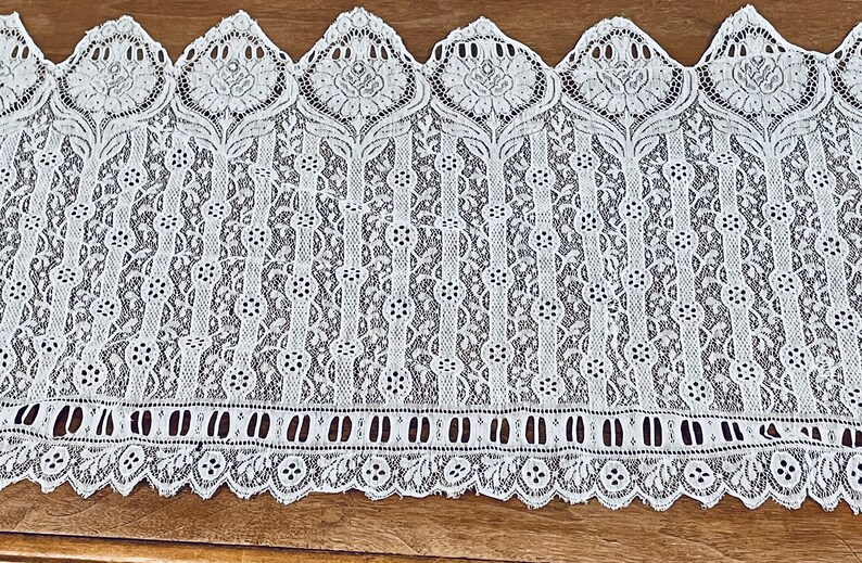May include: White lace trim with a scalloped edge and a repeating floral pattern.