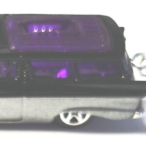 May include: A miniature hearse keychain. The toy car is black and silver with a purple tinted roof and windows. The keychain has a silver metal ring attached to the car.