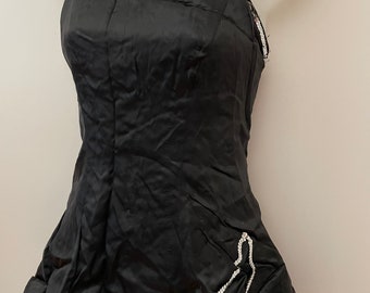 May include: Black satin top with silver sequin trim. The top features a fitted bodice and a flared skirt. The straps and neckline are embellished with silver sequins. The garment is displayed on a mannequin.