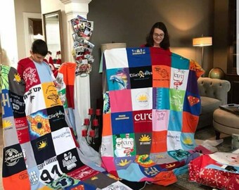 Puede incluir: Dos colchas de retazos coloridas hechas de camisetas. Las colchas están hechas de cuadrados de diferentes colores y patrones. Las colchas están siendo sostenidas por dos personas. Las colchas tienen las palabras "Ellie's Hats" y "cure" en ellas.