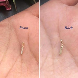 May include: A gold bar charm with small diamonds set into the front. The charm is shown from the front and back.