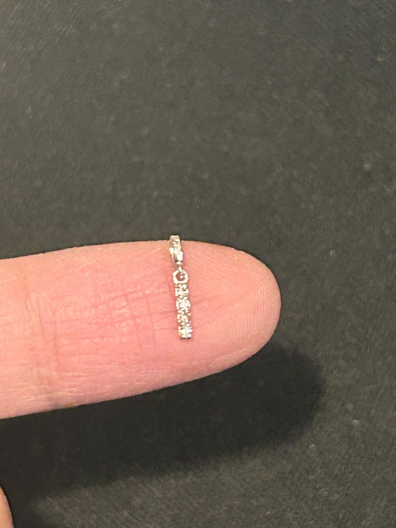 May include: A delicate silver chain with a row of small, clear gemstones hanging from it.