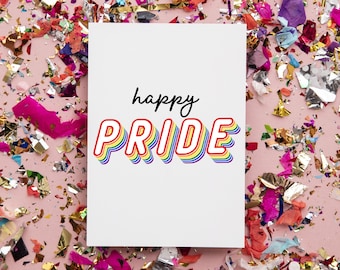 May include: A white card with the text "happy pride" in rainbow letters on a pink background with colorful confetti.