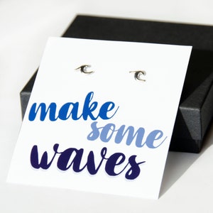 May include: A white card with the text "make some waves" in blue, purple, and light blue lettering. Two silver wave earrings are displayed on the card.