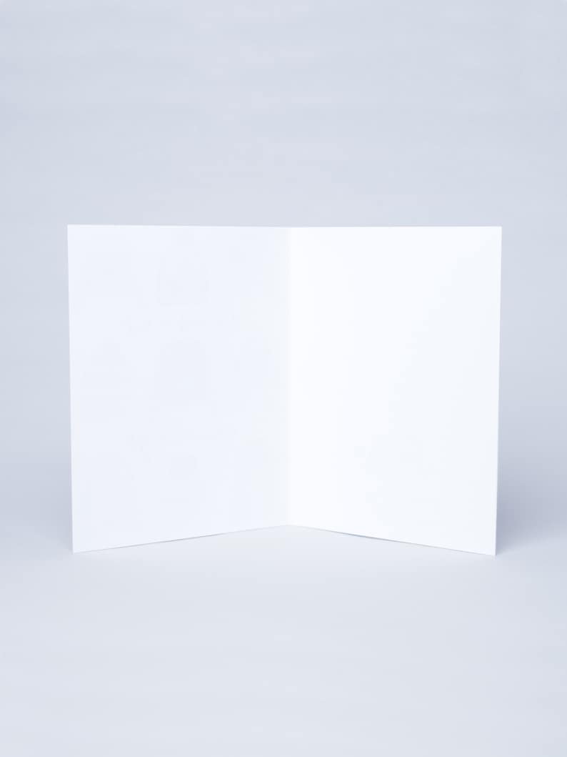 May include: A blank white card folded in half, ready for writing a message.
