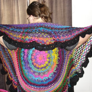 May include: A colorful crocheted shawl with a black trim. The shawl is made with a variety of different colored yarns and has a circular design.