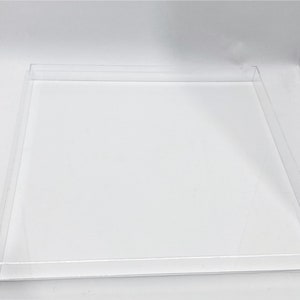 May include: A clear acrylic square tray. The tray is empty and has a smooth surface.
