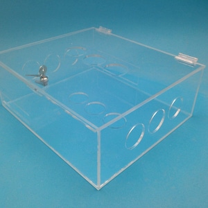 May include: A clear plastic box with a lock and key. The box has multiple round holes in the sides and bottom.