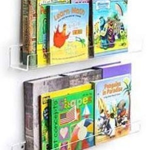 May include: Two clear acrylic wall-mounted shelves for displaying books. The shelves are designed to hold books upright and are attached to the wall with screws.