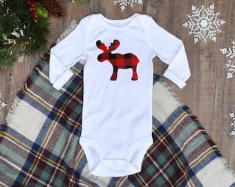 Op de afbeelding: Witte babybody met lange mouwen. De body heeft een rood-zwart buffelruit elandontwerp op de voorkant. De body ligt op een geruite deken met een kerstthema.