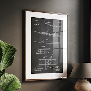 Może przedstawiać: Czarno-biały, vintage'owy rysunek patentowy projektu łodzi. Rysunek jest oprawiony i wisi na ciemnej ścianie nad drewnianym biurkiem z lampą.