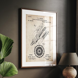 Peut inclure: Une impression de style vintage d'un brevet pour une dynamo ou une machine électrique magnéto, inventée par T.A. Edison et brevetée le 10 septembre 1883. L'impression est encadrée dans un cadre noir et est accrochée à un mur sombre.