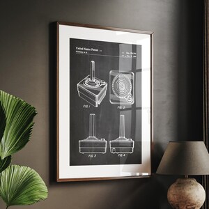 Op de afbeelding: Een zwart-witte vintage patenttekening van een joystick-controller. De tekening toont vier verschillende aanzichten van de controller, gelabeld FIG. 1 tot en met FIG. 4. Het patentnummer is 3,914,015 en de datum is 24 december 1975.