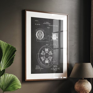 Może przedstawiać: Oprawiony wydruk schematu patentowego modelu prądu przemiennego Tesli. Czarno-biały plan jest wyświetlany w brązowej drewnianej ramie. Wydruk znajduje się na drewnianym biurku z lampą i książkami.