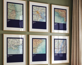 Puede incluir: Seis mapas enmarcados de diferentes ciudades, incluyendo Dublín, Nueva Orleans y Nueva York, se muestran en una pared verde. Los mapas son de estilo vintage y tienen un fondo azul con texto blanco.