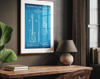 May include: Framed blueprint art print of a bass guitar patent. The blue and white design is displayed in a wooden frame. The text "United States Patent Office" is visible at the top. The print is displayed on a dark wall above a wooden desk.