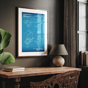 May include: Framed blueprint patent art print. The print features a detailed technical drawing of a device, with the text "United States Patent" at the top. The artwork is displayed in a wooden frame, adding a touch of vintage charm to the decor.
