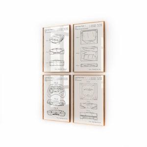 May include: Four framed patent prints featuring detailed technical drawings of a video game console and controller. The prints are in black and white, with a light background and wooden frames. The drawings include various views and components of the console.