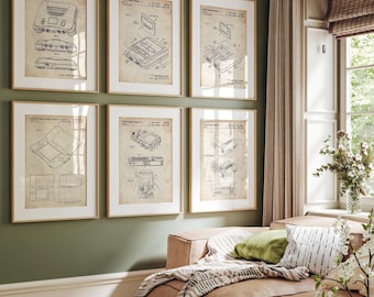 May include: Six framed vintage video game patent prints. The prints feature detailed technical drawings of classic gaming consoles and handheld devices. The frames are a light wood color, and the background is a muted green.