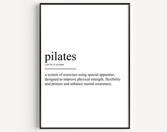 May include: A framed print with the word "pilates" in a bold, black font. Below the word is the phonetic pronunciation and a definition of pilates, describing it as a system of exercises for physical strength, flexibility, and posture.