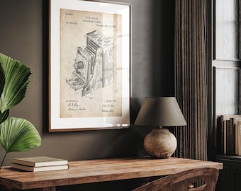 Op de afbeelding: Een ingelijste vintage camera patent print. De print toont een gedetailleerde technische tekening van een camera, met tekst waaronder de naam "T.R. Blair" en de datum "19 mei 1885". De print zit in een bruine houten lijst.