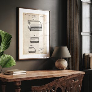 May include: Framed vintage patent print featuring three technical drawings of a food display case. The print is in a wooden frame and hangs on a dark wall. The print has a beige background with black text and illustrations.