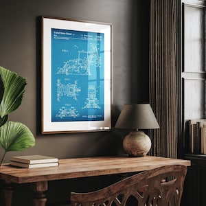 May include: Framed blueprint patent art print featuring a detailed technical drawing of a machine, set against a blue grid background. The print includes the text "United States Patent" and various technical diagrams. The frame is a warm brown color.