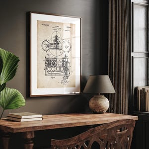 May include: Framed vintage blueprint of an engine, featuring detailed mechanical diagrams in black ink on aged paper. The frame is a dark brown wood, and the print is displayed on a wooden desk with a lamp.