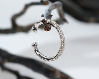 May include: A silver ear cuff with a row of small, clear diamonds around the edge.