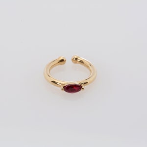 May include: Gold ear cuff with a single red marquise-shaped gemstone.