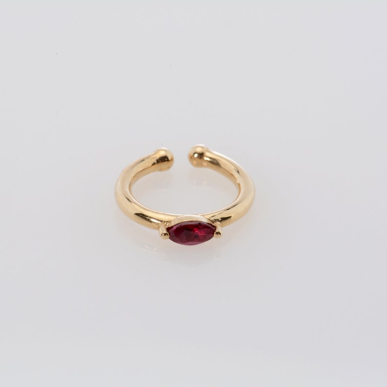 May include: Gold ear cuff with a single red marquise-shaped gemstone.