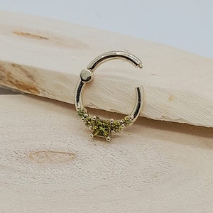 May include: A gold hoop earring with a row of small green gemstones and a larger square-shaped green gemstone in the center.