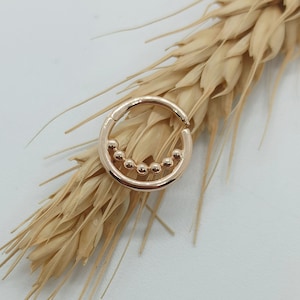 May include: A gold-toned hoop earring with a row of small, round beads along the bottom edge.