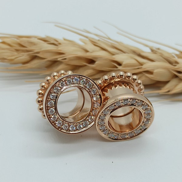 May include: A pair of gold-toned ear gauges with a circle of clear rhinestones around the outer edge. 