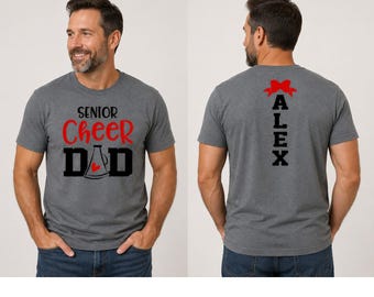 Könnte beinhalten: Ein anthrazitfarbenes Kurzarm-T-Shirt mit dem Text SENIOR CHEER DAD auf der Vorderseite, einer Megafon-Grafik und einem kleinen roten Herz. Auf der Rückseite steht der Name ALEX in schwarzen vertikalen Buchstaben, gekrönt von einer roten Schleife.