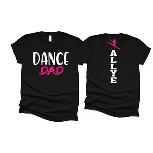 May include: Two black t-shirts. One has "DANCE DAD" in white and pink lettering. The other has the name "ALLYE" in white, with a pink dancer graphic. Both shirts are short-sleeved.