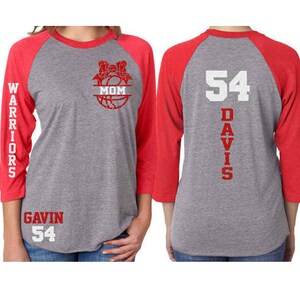 Pu&ograve; includere: Una maglietta da baseball grigia e rossa con un design a pallacanestro sul davanti e la parola "MOM" all'interno della pallacanestro. La parte posteriore della maglietta ha il numero "54" e la parola "DAVIS" verticalmente sul retro. La manica sinistra ha la parola "WARRIORS" verticalmente sulla manica. La parte anteriore della maglietta ha anche il nome "GAVIN" e il numero "54" stampato in basso a sinistra.