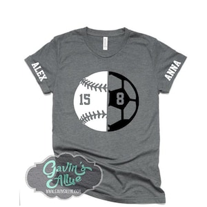 May include: Gray t-shirt featuring a baseball and soccer ball design. The baseball half has the number 15, and the soccer ball half has the number 8. The sleeves have the names "ALEX" and "ANNA". The shirt also has the text "Gavin's Allye" and a website address.