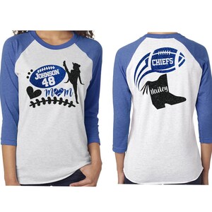 May include: Two white and blue baseball shirts. The left shirt has a football with the text "Johnson 48" and a cheerleader silhouette with a heart and the text "Mom". The right shirt has a football with the text "Chiefs" and a boot with the text "Hailey".
