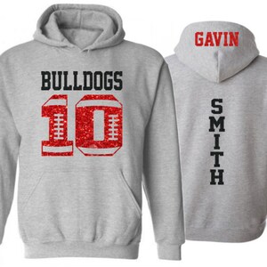 May include: Gray hooded sweatshirt with red glitter football number 10 and the word "BULLDOGS" on the front. The back of the sweatshirt has the name "GAVIN SMITH" printed vertically.