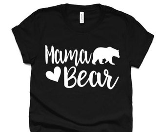 May include: Black t-shirt with white text that says "Mama Bear" and a white silhouette of a bear walking to the right. A white heart is between the words "Mama" and "Bear".