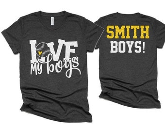 May include: Two dark gray t-shirts with white text. One shirt says "LOVE my boys" with a baseball graphic. The other shirt says "SMITH BOYS!" in yellow glitter.