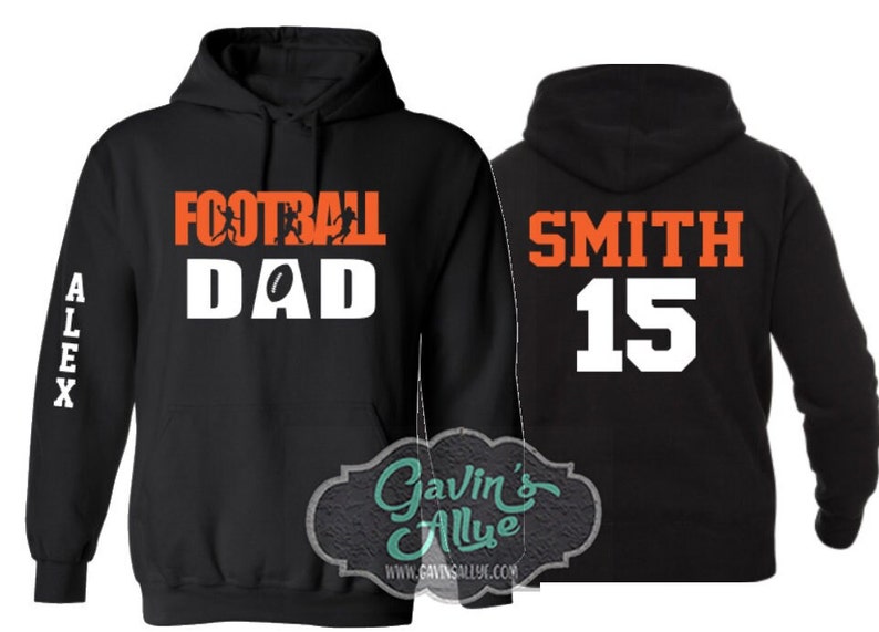 May include: Black hooded sweatshirt with the text "Football Dad" in white with orange football players and a football on the front. The left sleeve has the name "Alex" in white. The back of the sweatshirt has the text "Smith 15" in white with orange outlines.