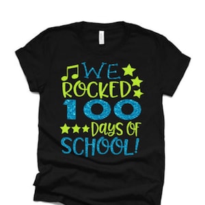 May include: Black t-shirt with a green and blue glitter design that says "We rocked 100 days of school!"